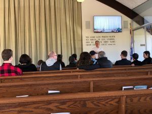A group of people are sitting in a church listening to a sermon.