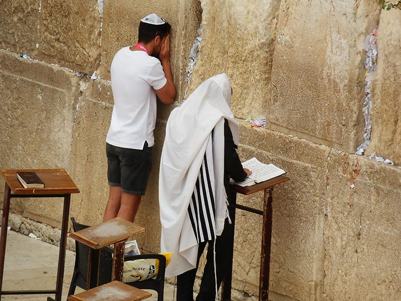 A man and a woman are praying at the wailing wall