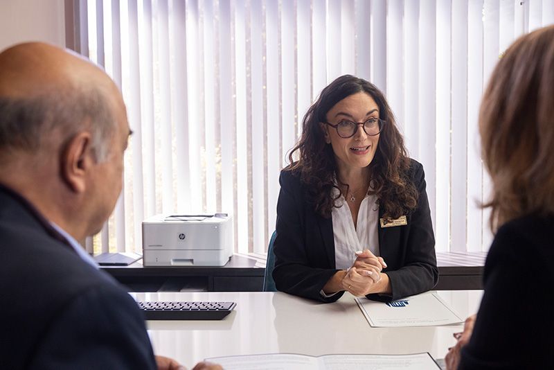 A woman is sitting at a table talking to two men.