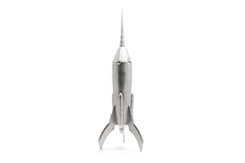A silver model of a rocket with a long pointed tip