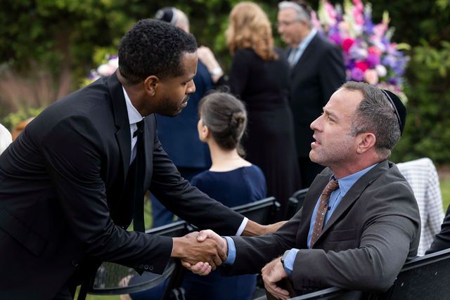 Two men in suits are shaking hands at a funeral.
