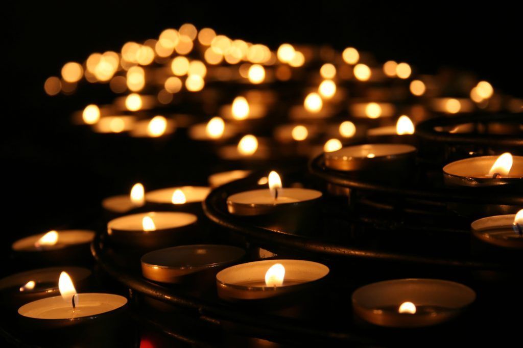 A bunch of candles are lit up in a dark room.