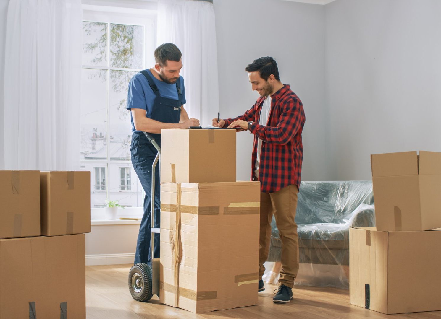 Deux hommes emballent des cartons dans un salon.