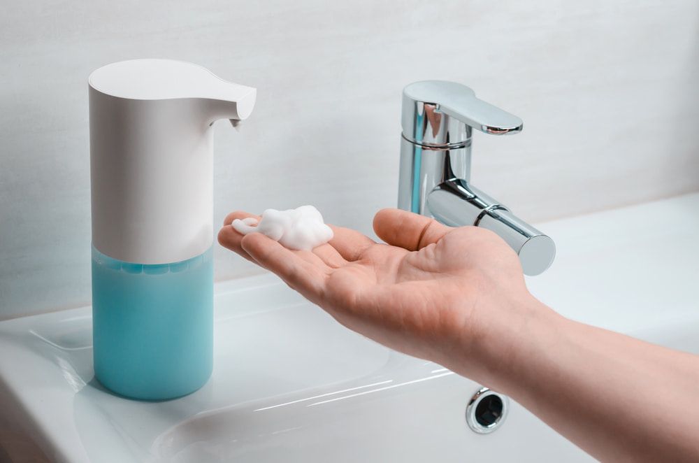 A Person Is Washing Their Hands In A Bathroom Sink — Aafco Hygiene In Wodonga, VIC