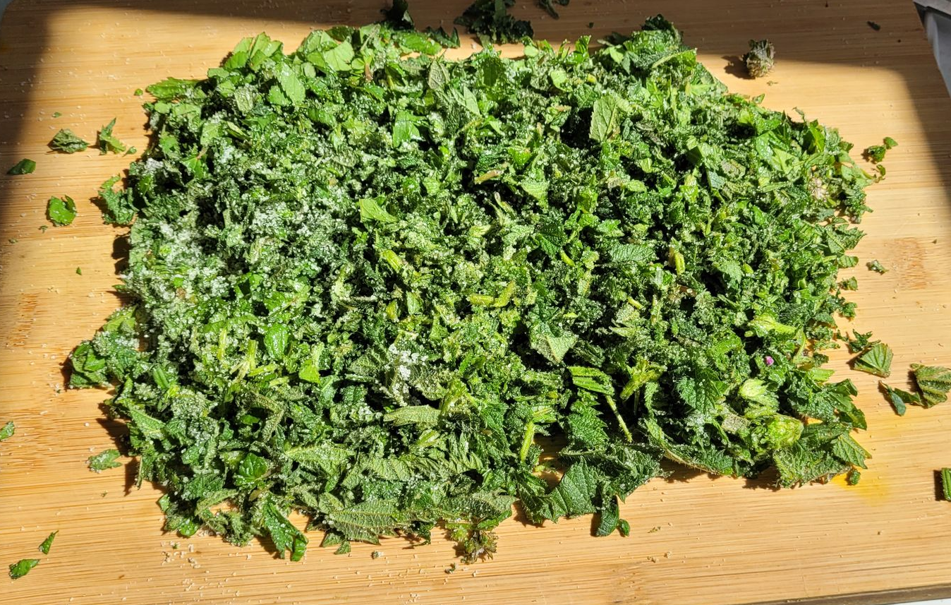 Gesneden groene kruiden verspreid over een houten snijplank.