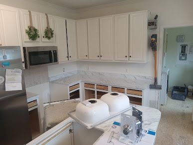 A kitchen with white cabinets and marble counter tops is being remodeled.