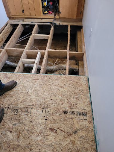 A person is standing on a wooden floor under a cabinet.