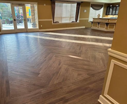 A large room with a wooden floor and a herringbone pattern.