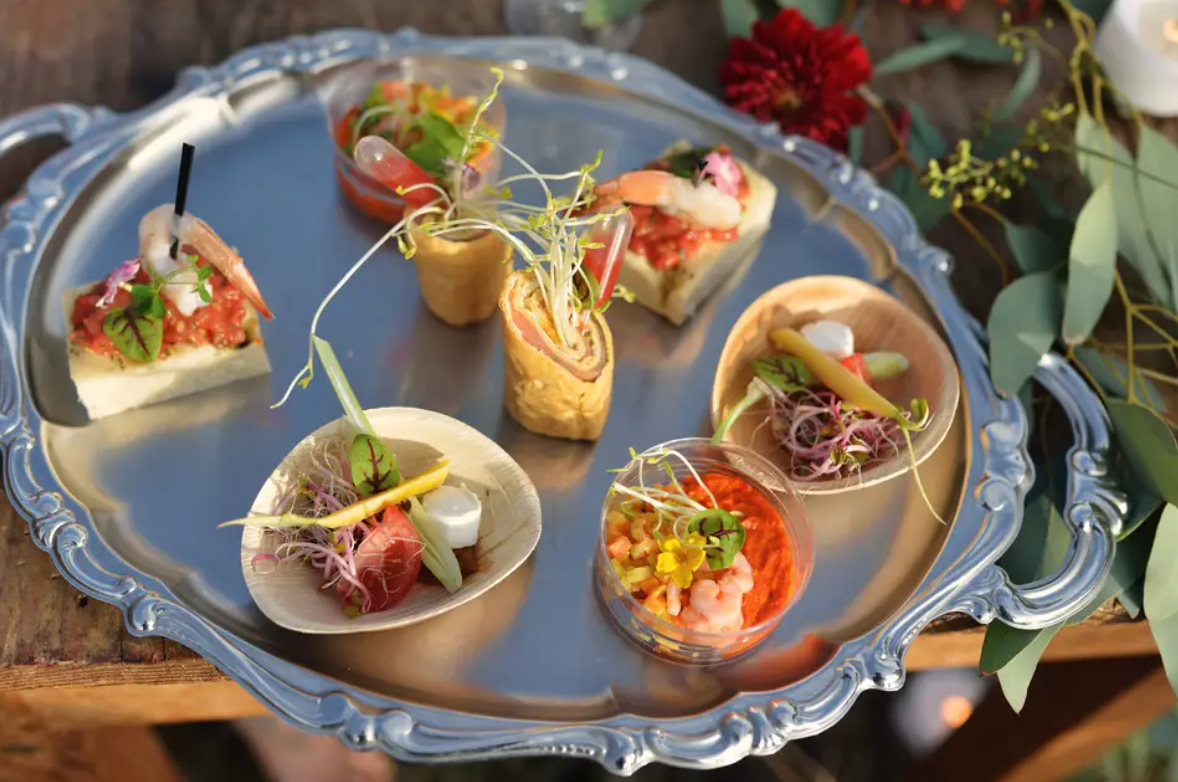 Un plateau en argent rempli de différents types d'aliments sur une table en bois.
