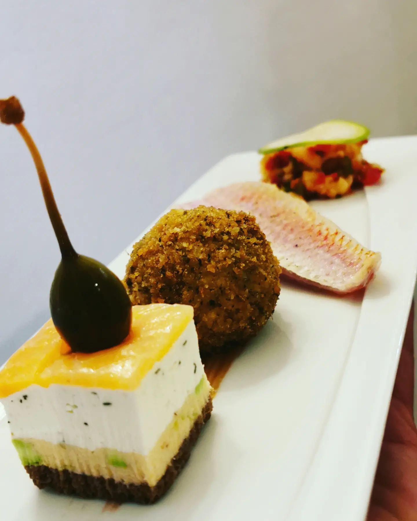 Une personne tient une assiette blanche avec trois desserts dessus