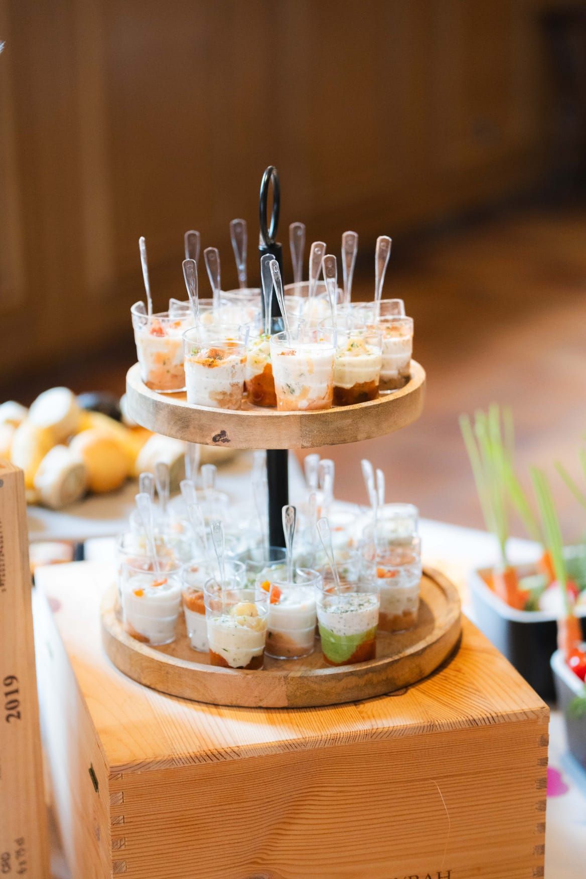 Un plateau en bois rempli de petites tasses de nourriture sur une table.