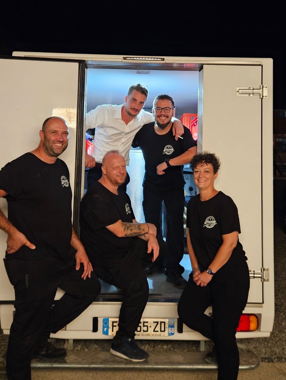 Un groupe de personnes pose pour une photo devant un camion blanc.