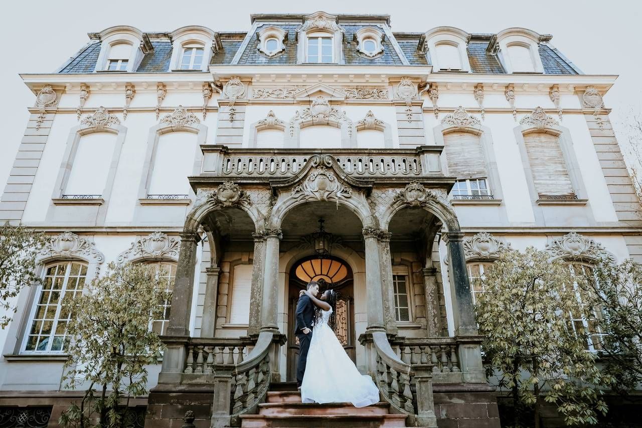 Une mariée et un marié s'embrassent devant un grand bâtiment.
