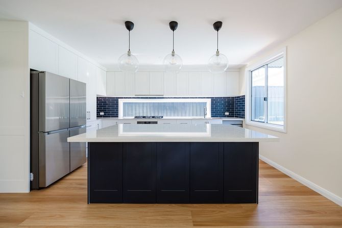 Modern kitchen in granny flat build at Brown Street Redhead with white cabinetry and engineered stone benchtop