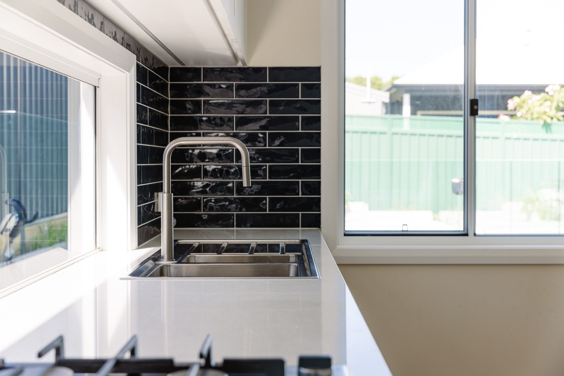 A modern bathroom vanity with a white vessel sink, dark metal faucet, and soap dispenser against gray terrazzo-style tile.