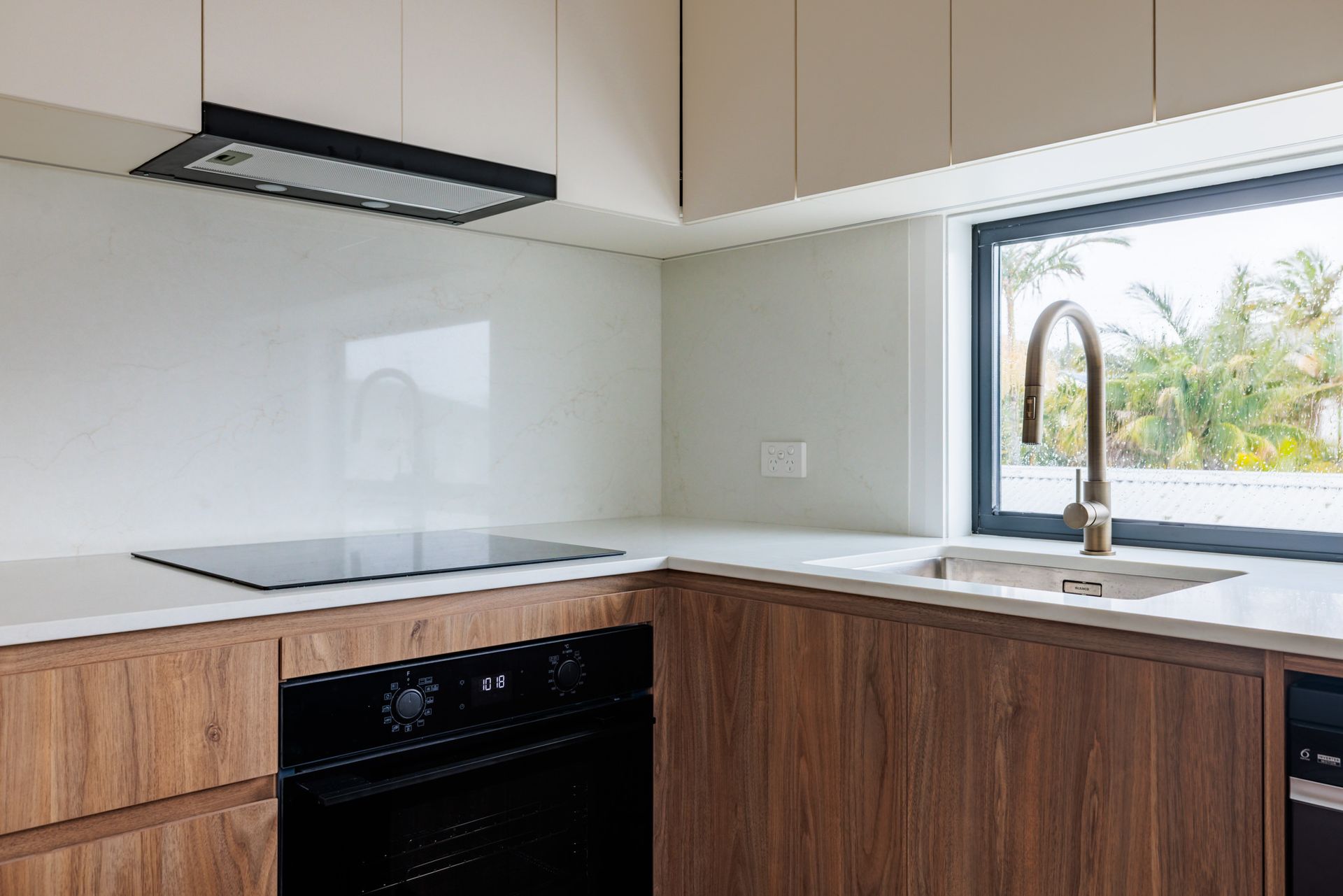 A modern kitchen featuring a dark island with a white countertop, three pendant lights, and a stainless steel refrigerator.