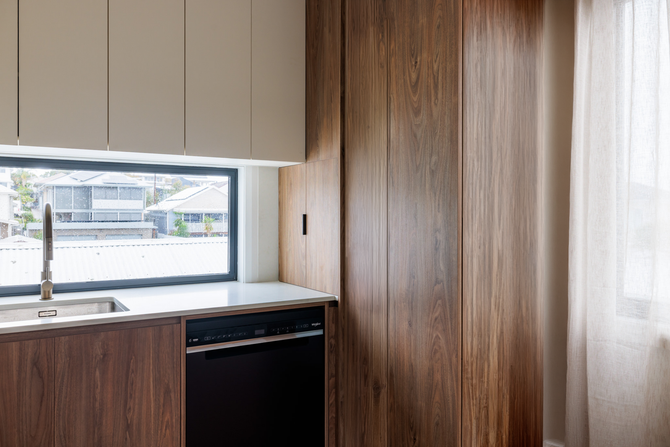 Modern kitchen in granny flat build at Brown Street Redhead with white cabinetry and engineered stone benchtop