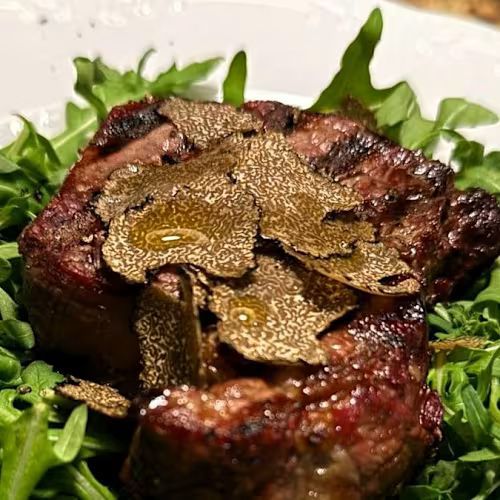 Bistecca alla griglia con scaglie di tartufo su un letto di verdure