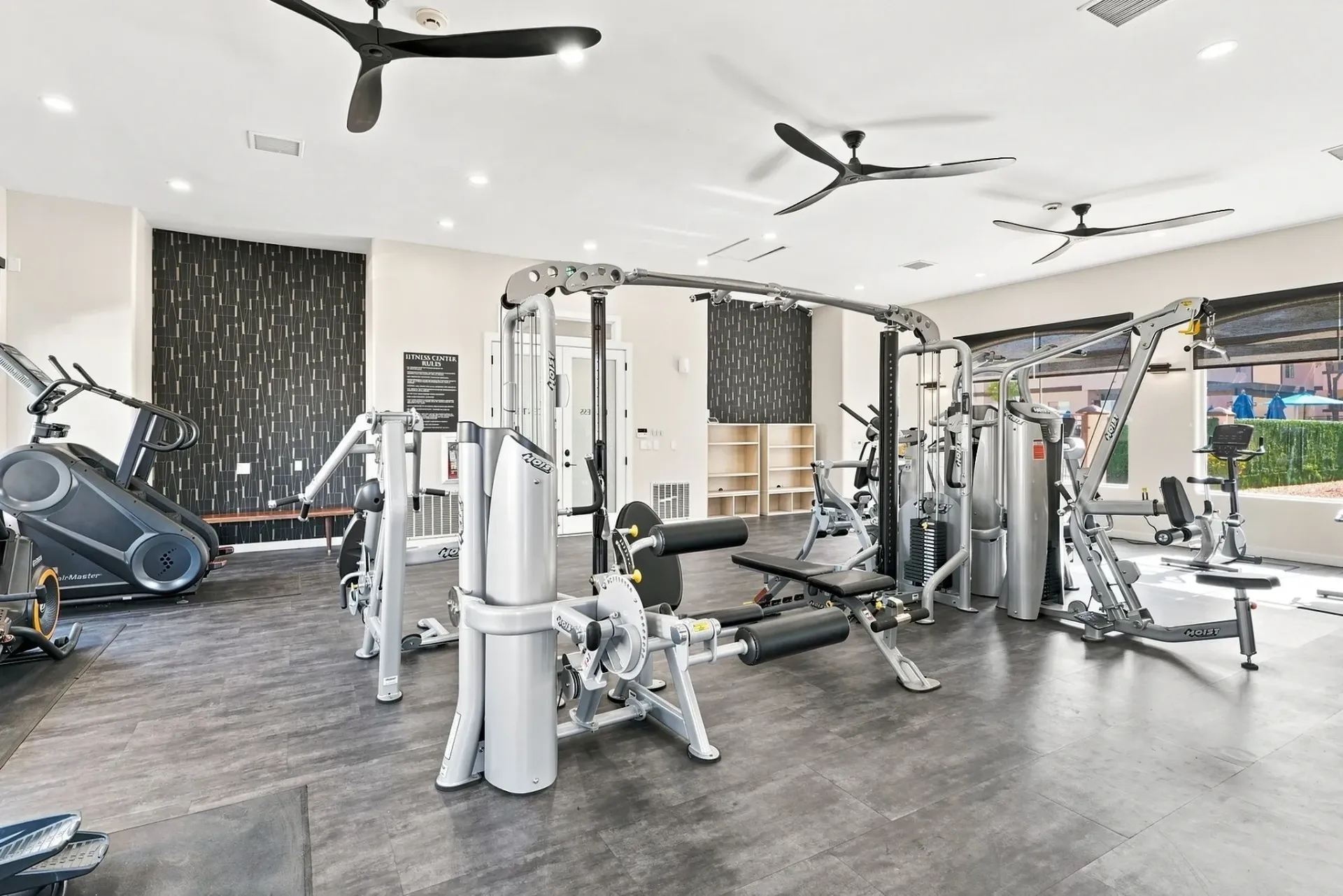 Interior of a modern apartment complex gym with various weight machines and cardio equipment.