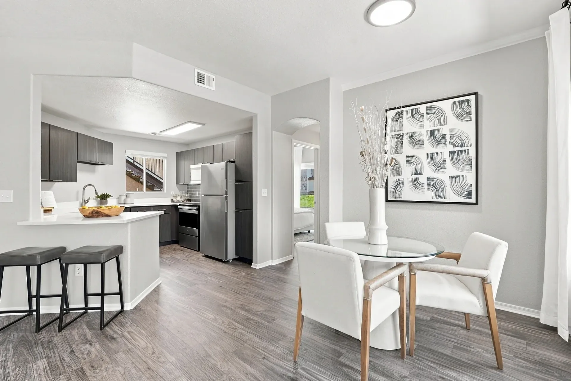 Modern kitchen and dining area with gray cabinets, stainless steel appliances, and a round glass dining table at Broadstone Heights, offering apartments in Albuquerque, NM.