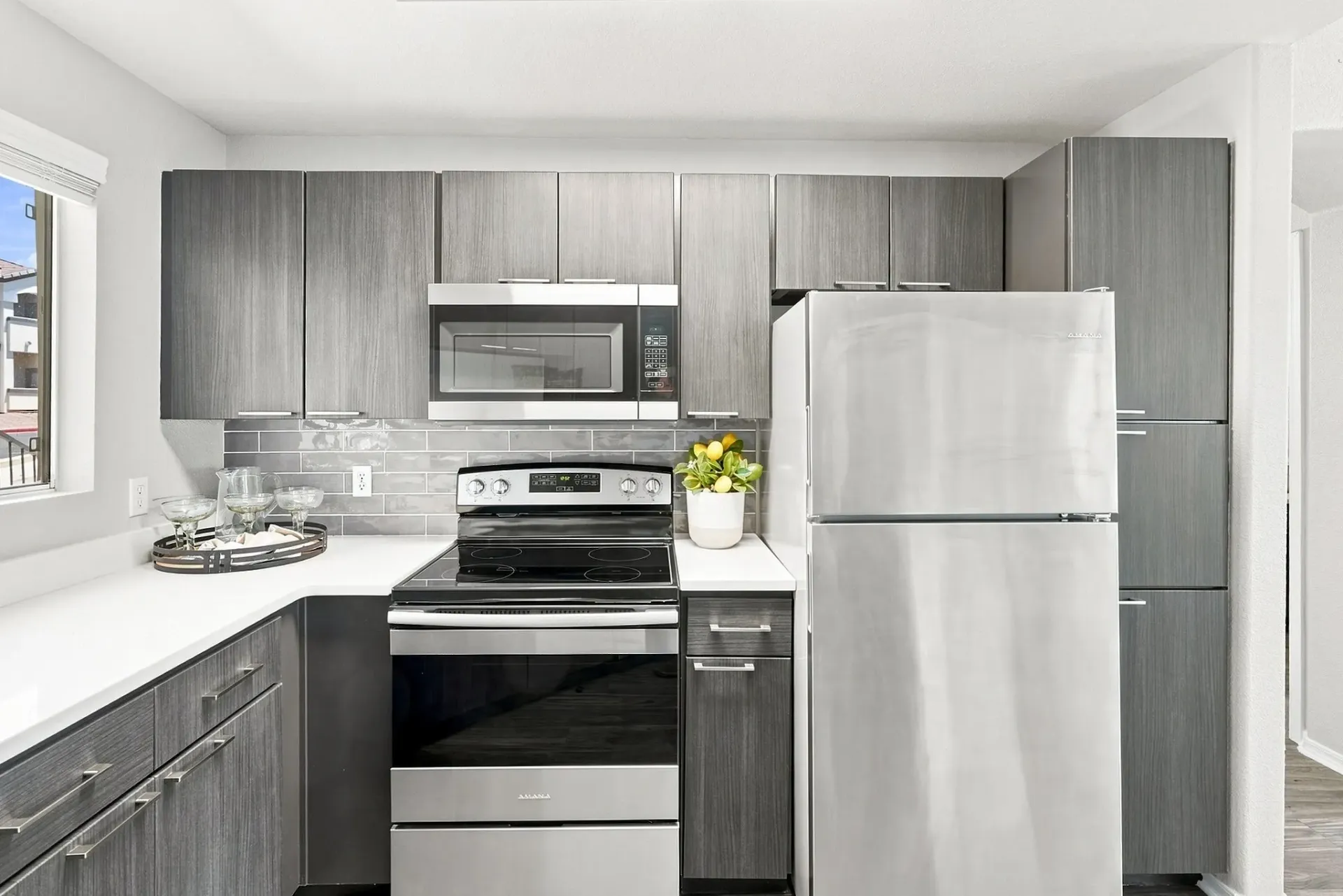 Modern kitchen with stainless steel appliances and gray wood cabinets.