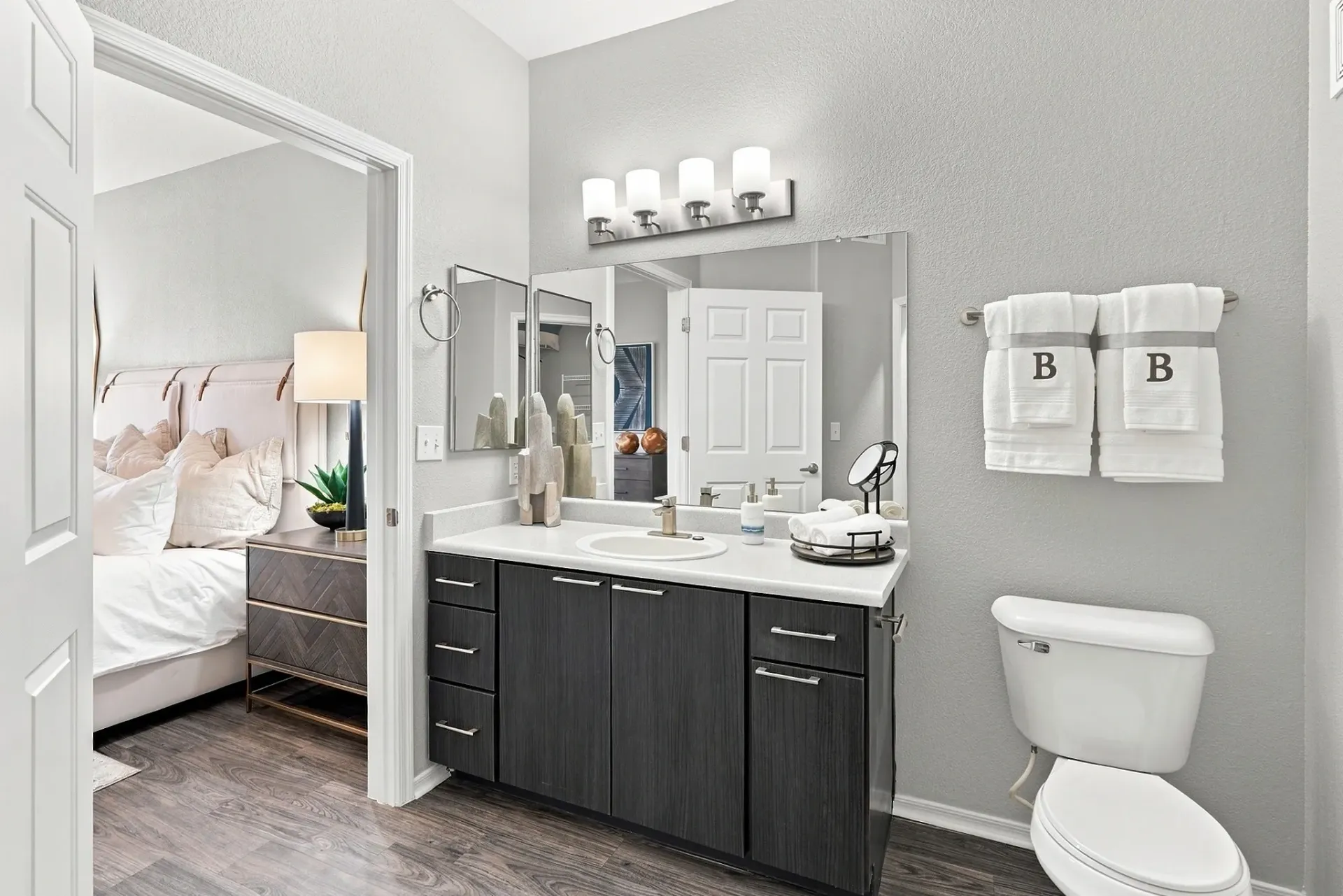 Bathroom vanity with a sink, dark wood cabinets, and a large mirror. A toilet is visible to the right at Broadstone Heights, offering apartments in Albuquerque, NM.