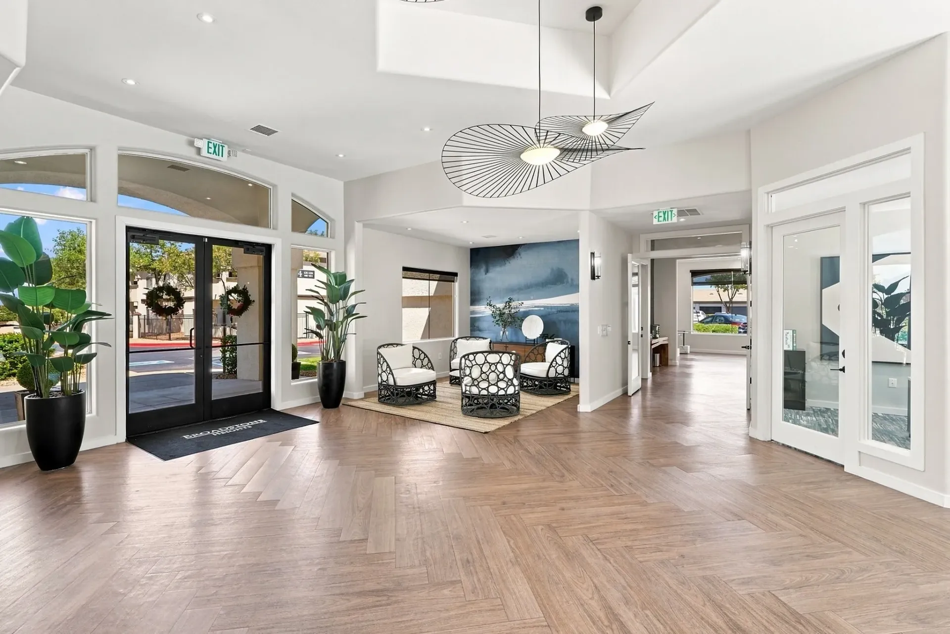 Modern apartment building lobby with double glass doors, seating area, and decorative lighting at Broadstone Heights, offering apartments in Albuquerque, NM.