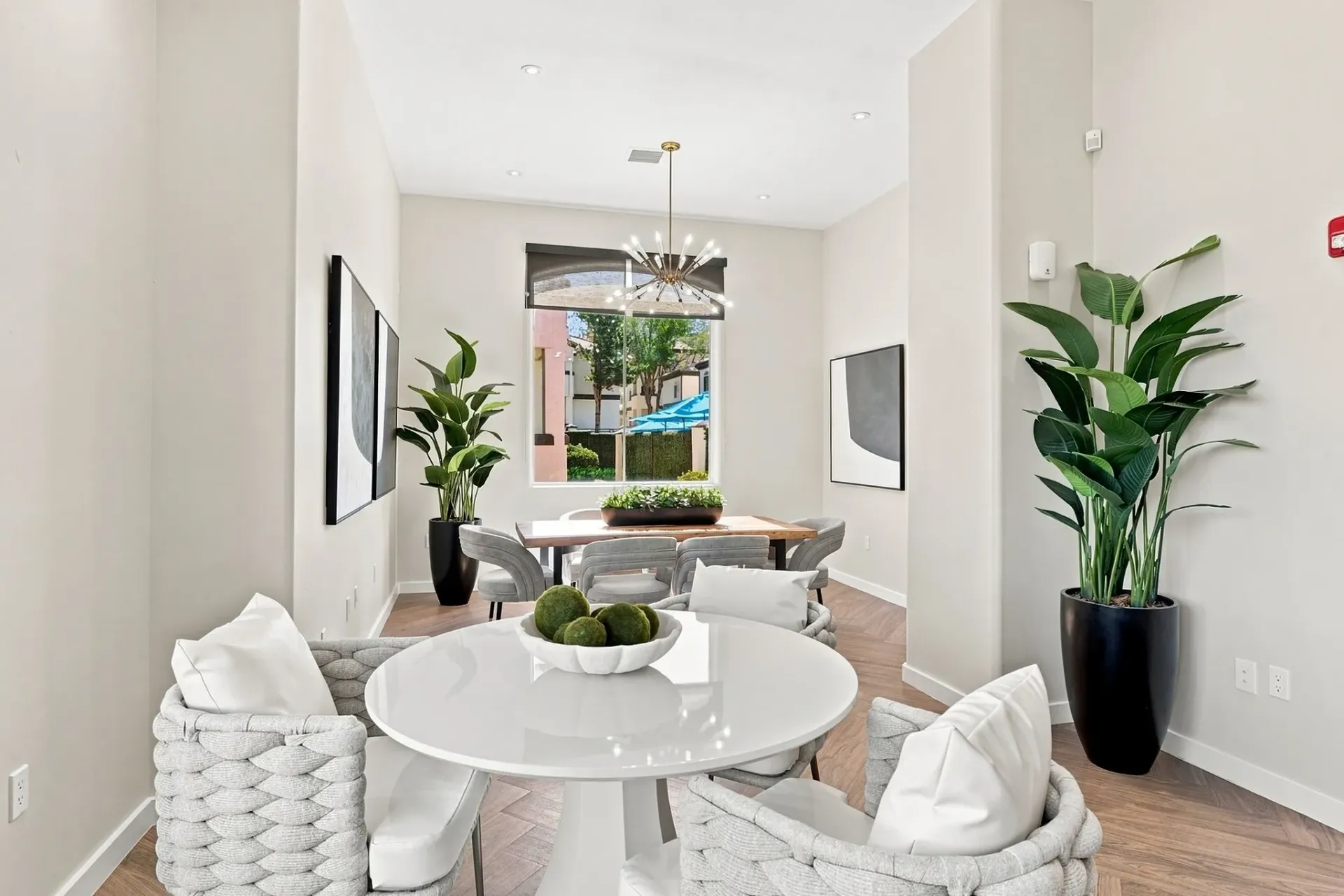 Modern lounge area with a round table, comfortable seating, and a dining table by the window at Broadstone Heights, offering apartments in Albuquerque, NM.