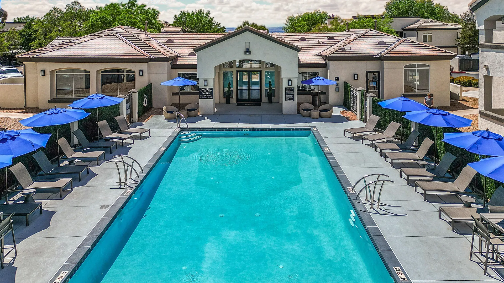 Resort-style swimming pool with lounge chairs and umbrellas at Broadstone Heights, offering apartments in Albuquerque, NM.