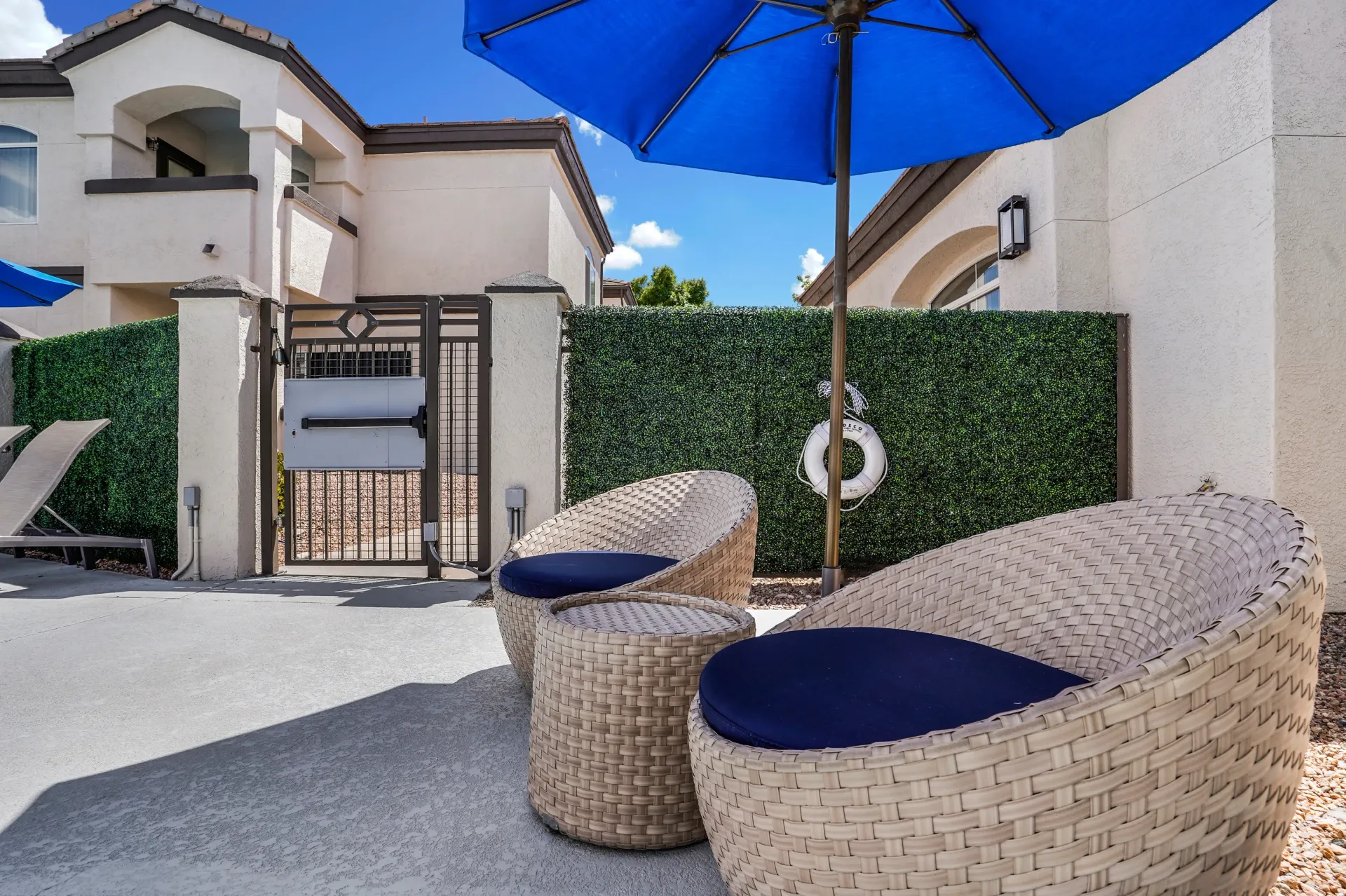 Outdoor seating area with blue umbrellas and a life preserver at Broadstone Heights, offering apartments in Albuquerque, NM.