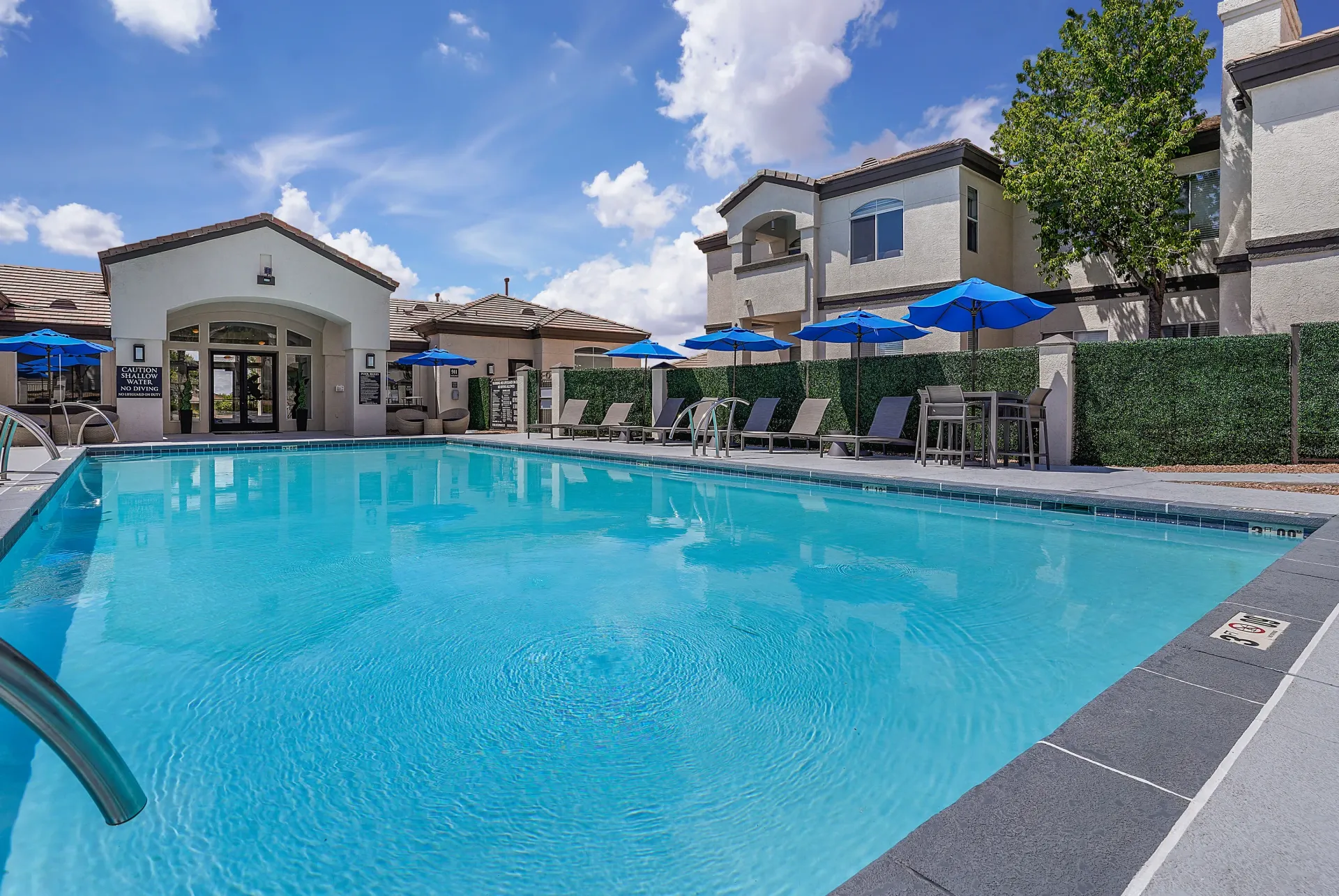 Swimming pool with lounge chairs and umbrellas at Broadstone Heights, offering apartments in Albuquerque, NM.