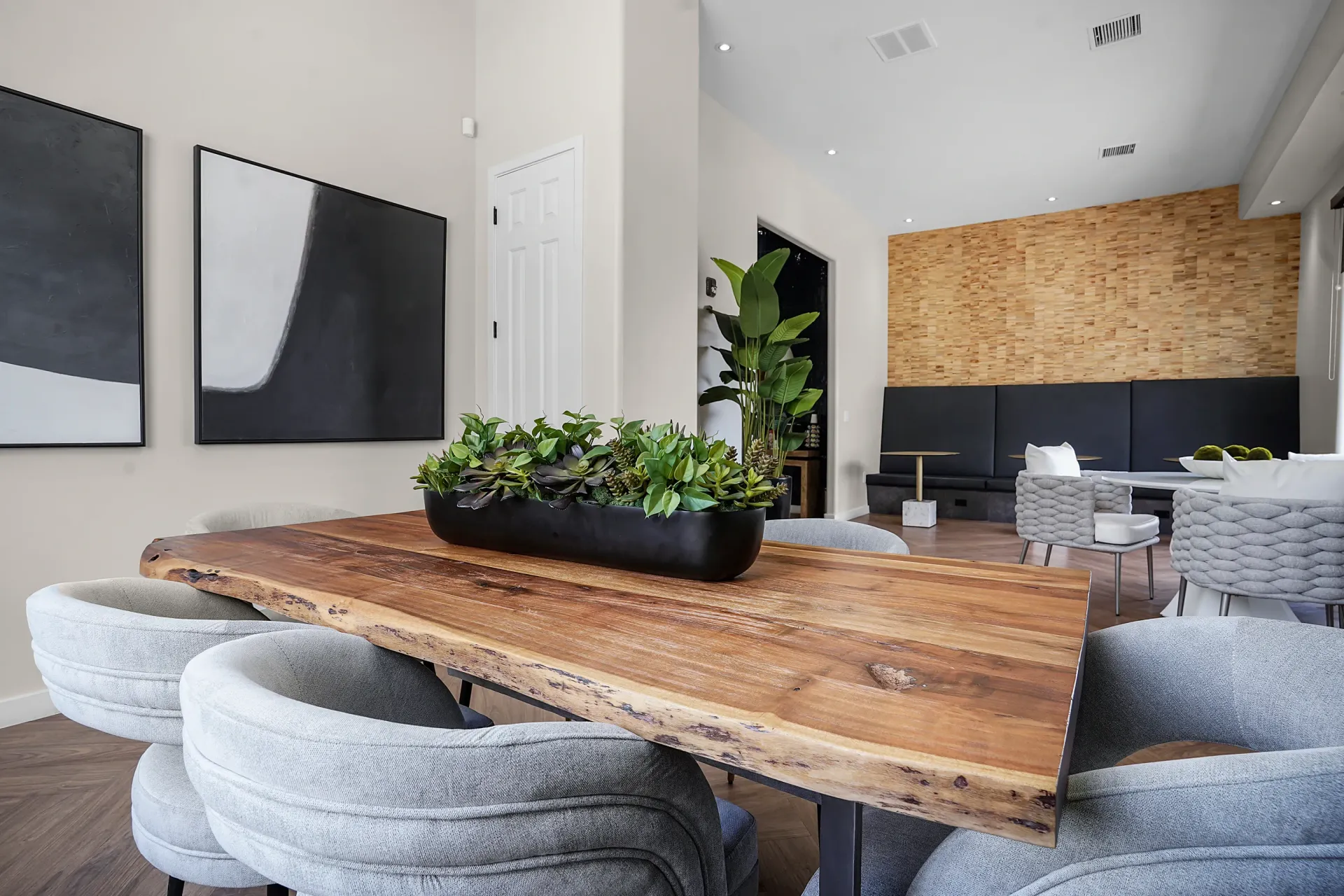 Live-edge dining table with grey chairs, modern art on wall, and textured wood paneling in community lounge at Broadstone Heights, offering apartments in Albuquerque, NM.