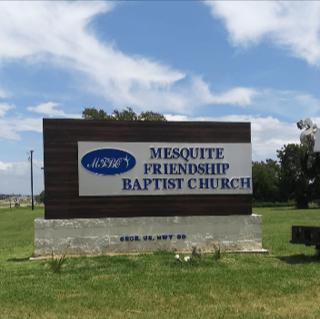 Mesquite Friendship Baptist Church sign on a grassy roadside under a blue sky