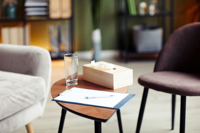 Living room with a wooden coffee table, water glass, tissue box, sofa, and chair.