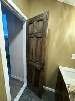 Wooden interior door ajar in room with beige walls and a white door frame.