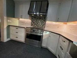 Kitchen with white cabinets, stainless steel appliances, and a mosaic backsplash.