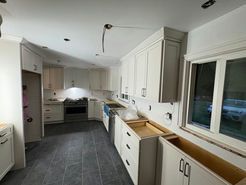 Kitchen under renovation with white cabinets, dark tile floor, and a window.