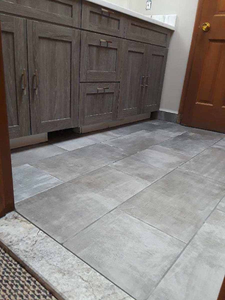 Gray tiled bathroom floor with a wooden vanity and door.