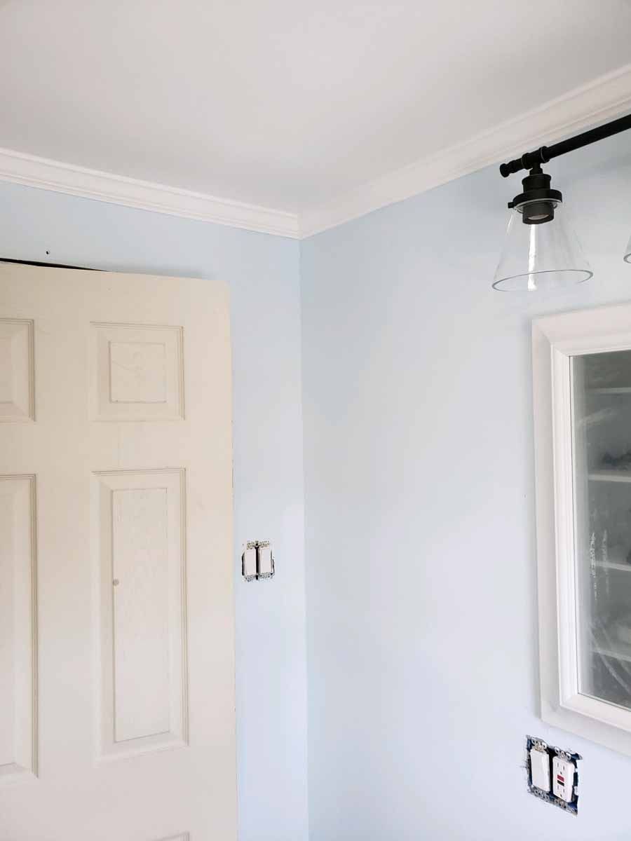 Interior corner with a white door, light blue walls, and a window. Black track lighting.