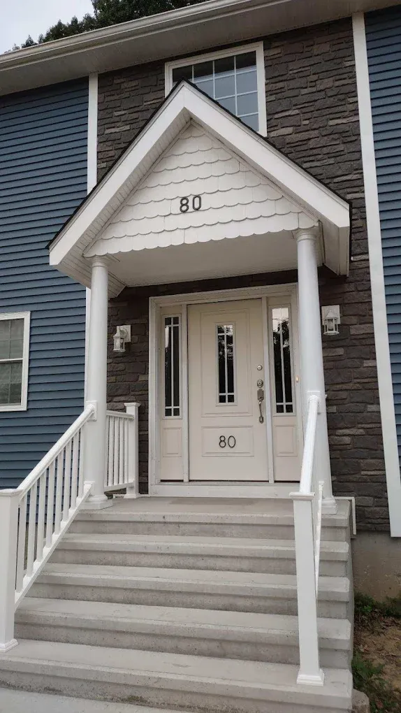 House entrance with white columns, steps, door, and address "80." Blue and stone siding.