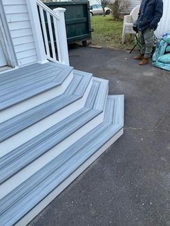 Gray and white steps leading to a house. A person stands nearby.