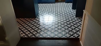 A hallway with black and white patterned tile flooring. Dark blue cabinets are visible in the background.