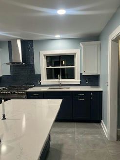 Newly renovated kitchen with blue cabinets, white countertops, and stainless steel appliances.