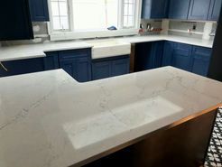 Kitchen with white countertops, blue cabinets, and a white sink.