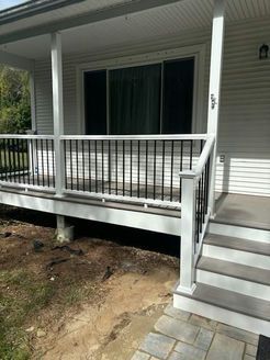 White porch with black railing and gray steps leading up to sliding glass door.