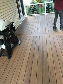 Composite deck with a grill and person standing on it near a railing.