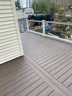 Composite deck with white railing, overlooking a yard with a garage and van.
