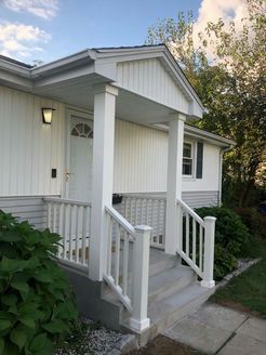White house entrance with steps, porch, and railing.