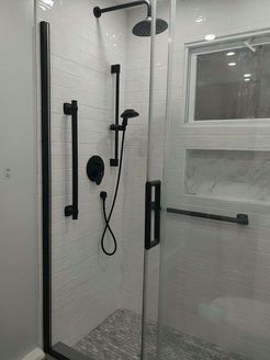Modern shower with black fixtures and white tiled walls, including a grab bar.