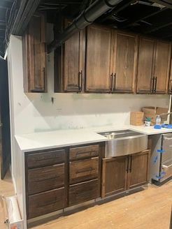 Kitchen cabinets: dark wood uppers, dark brown lowers, white countertop, stainless steel sink.
